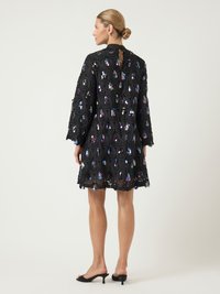 Μαύρο φόρεμα με κυκλικό σχέδιο, διακοσμημένο με ιριδίζουσες σταγόνες, μακριά μανίκια και άνοιγμα στη πλάτη. Λείος υφή και μήκος έως το γόνατο.