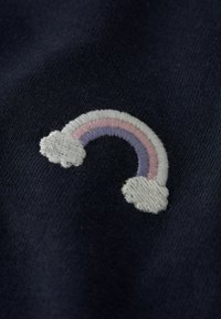 Granatowa tkanina z małą haftowaną tęczą o łukach w kolorach różowym, fioletowym i białym, ozdobiona dwoma puszystymi białymi chmurkami na końcach.