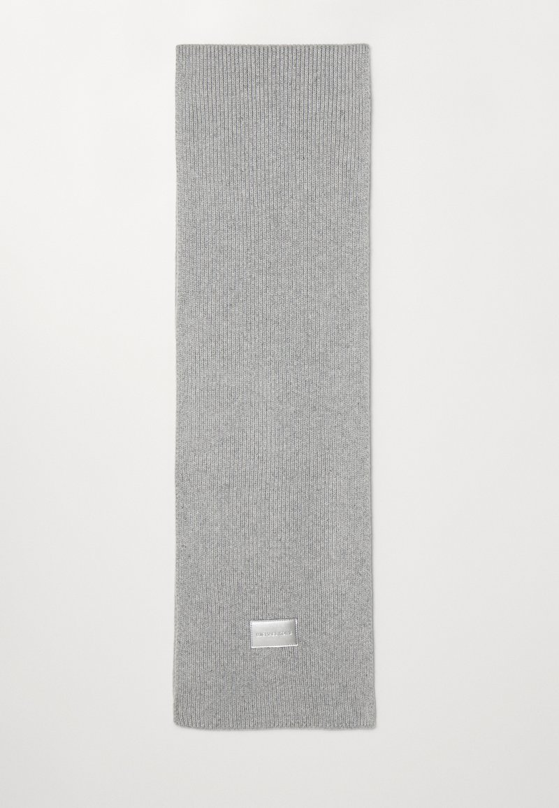 Sciarpa in lana lavorata a maglia di colore grigio chiaro con una piccola etichetta rettangolare argentata vicino a un'estremità su uno sfondo bianco.