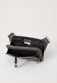 Portefeuille gris zippé avec compartiments doubles, un extérieur texturé et un intérieur noir avec un motif de logo en répétition. Sangle réglable incluse.