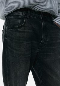 Jeans in denim nero con taglio dritto, dotati di un design a cinque tasche e leggeri effetti di sbiaditura. Tessuto testurizzato con un classico dettaglio di rivetti.