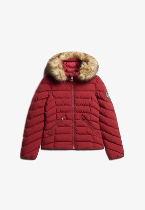 Veste rembourrée rouge avec une capuche en fausse fourrure, fermeture éclair à l'avant et texture matelassée. Elle possède deux poches latérales zippées et un patch logo sur la manche.