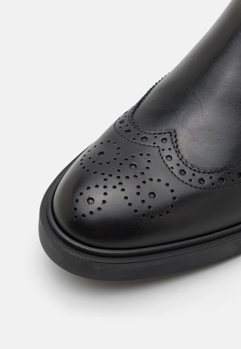 Schwarzer Lederschuh mit einer perforierten Brogue-Design auf der Zehenpartie, mattem Finish und einer Gummisohle. Glatte Textur mit ordentlichem Stich.