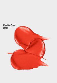 Krem w kolorze koralowym o gładkiej, błyszczącej teksturze. Produkt jest wymieszany na jasnym tle, z etykietą "Kiss Me Coral (750)."