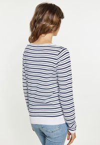 Pulover rayé cu dungi orizontale albastre și albe, decolteu rotund, mâneci lungi și manșete și tiv din tricot. Fabricat dintr-un material moale.