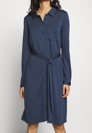 Granatowa sukienka zapinana na guziki, z długimi rękawami, kieszenią na piersi i paskiem wiązanym w talii. Miękka tkanina o gładkiej fakturze i luźnym kroju.