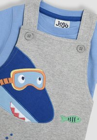Grå overalls med blå og aqua detaljer, der har et hajdesign med en orange maske. Inkluderer en blå t-shirt med korte ærmer under.