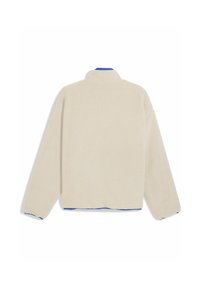 Fleece-takki vaaleassa kermassa, pehmeällä ja tekstuurilla pinnalla. Varustettu korkealla kauluksella ja sinisellä yksityiskohdalla helmoissa ja hihansuissa. Rentoa istuvuutta.