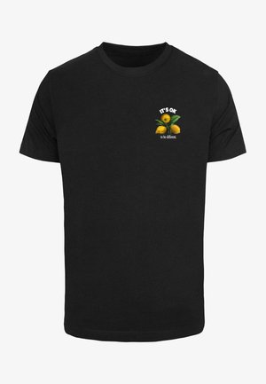 Sort bomulds T-shirt med et grafisk design af gule citrusfrugter og teksten "DET ER OK at være anderledes." Placeret på brystet.