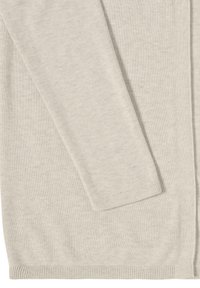 Manche et ourlet d'un cardigan en maille beige clair avec poignets et bords côtelés, montrant la texture du tissu et les détails de la couture.