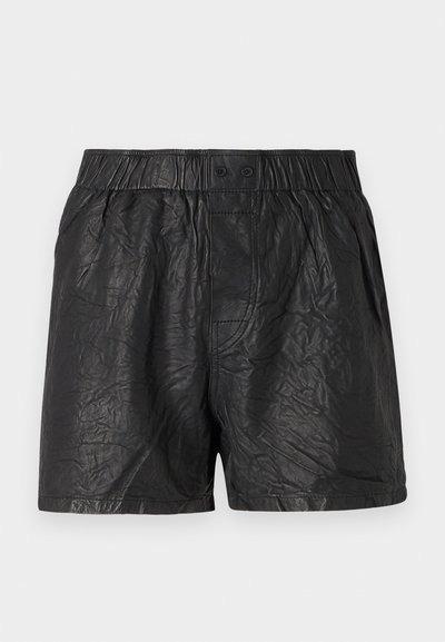 Zwarte shorts van gekreukt materiaal, met een elastische tailleband met twee knopen, knielange snit en een gladde textuur.