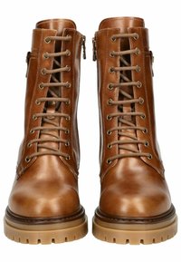 Bottines en cuir marron avec un design à lacets, fermeture éclair sur le côté et semelle en caoutchouc épaisse. Présente des œillets dorés et une texture lisse.
