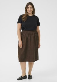 Black short-sleeve t-shirt paired with a brown knee-length skirt featuring an elastic waistband, textured fabric, and flat black shoes.