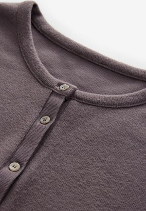 Cárdigan gris de punto con escote redondo, cierre de cuatro botones y una textura suave con un patrón sutil. Los botones son circulares y de color claro.