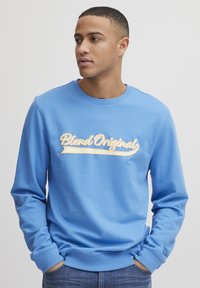 Sudadera azul clara de tejido suave, con "Blend Original" en un relieve estilizado en el pecho. Cuello redondo y mangas largas.