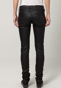 Svarta, åtsittande jeans i ett glänsande, elastiskt material, med bakfickor och en slät midja med snörningsdetalj.