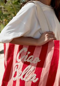 Torba tote w czerwono-różowe paski z teksturowanej tkaniny, z białym haftem "Ciao Bella" i plecionym uchwytem.
