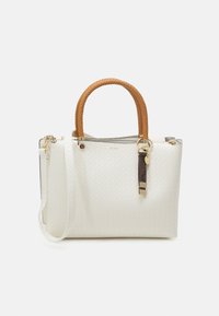 Sac fourre-tout tissé blanc avec une finition texturée, poignées tressées marron, accents métalliques dorés et étiquette décorative attachée. Bandoulière amovible.