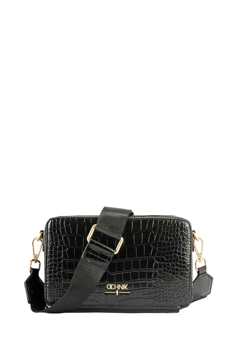 Czarna torebka crossbody z teksturą krokodyla, zdobiona złotymi akcentami. Posiada odpinany pasek oraz zamek błyskawiczny. Kompaktowy, prostokątny kształt.