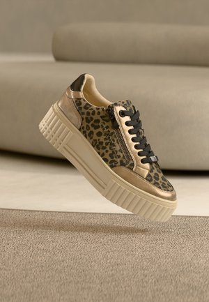 Chunky sneaker met luipaardprint, beige platformzool, zwarte veters en een zijrits, liggend op een gestructureerd beige tapijt.