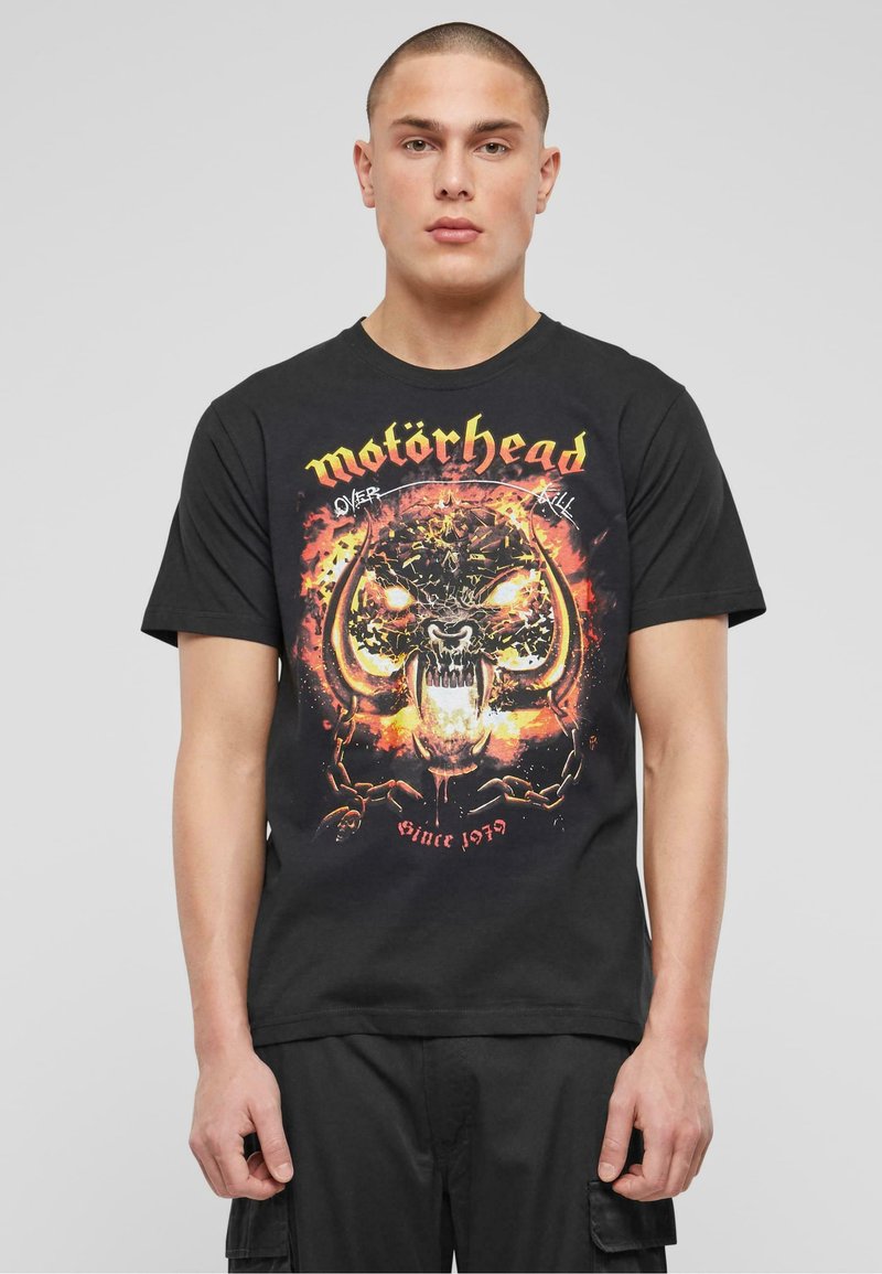 Černé bavlněné tričko s barevným grafickým potiskem lebky s rohy, plameny a nápisem "motörhead" nahoře ve žluté barvě. Obsahuje detail "od roku 1979".