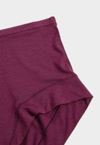 Culotte taille haute bordeaux en tissu doux et extensible. Texture lisse avec des coutures plates et sans matériel visible.
