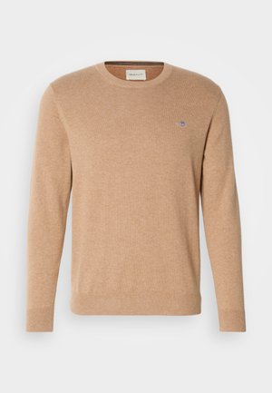 Beige sweater with a crew neckline, long sleeves, and ribbed cuffs, featuring a small embroidered logo on the chest.