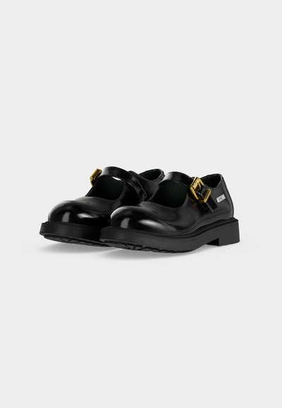 Chaussures Mary Jane en cuir verni noir avec boucles dorées et semelles épaisses sur fond blanc, montrant la vue de face et de côté.