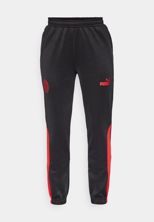 Mustad mustreenid punaste külgpaneelidega. Omab elastset vöökohta, kitsenevaid jalgu, Puma logo ja meeskonna embleemi ühel reiel.