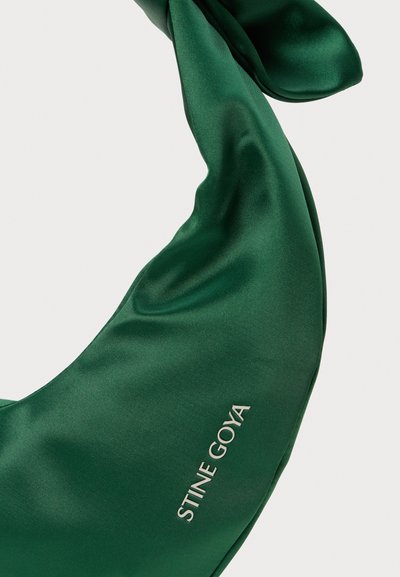 Zielony satynowy szal o gładkiej fakturze z nazwą marki "STINE GOYA" w srebrnym letteringach. Skręcony wzór z zwisającymi fałdami.