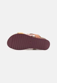 Daugiaspalvė šlepečių padas, pagamintas iš struktūrizuoto gumos, maroon spalvos, su iškilimais ir minimaliais ženklinimais; dirželiai geltonos, rožinės ir šviesiai rudų spalvų.
