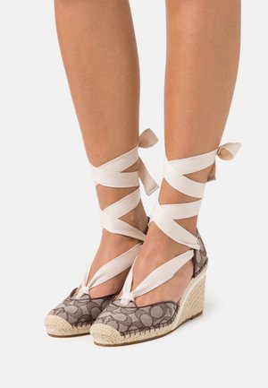 Brązowe espadryle na koturnie z wzorem, z plecioną jutaną podeszwą i kremowymi wstążkami owiniętymi wokół kostek, z zaokrąglonym noskiem.