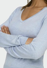 Maglione azzurro chiaro a scollo a V con maniche lunghe, realizzato in un morbido tessuto a maglia. Presenta polsini a coste e una superficie liscia. Senza motivi visibili.