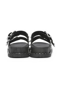 Schwarze Plateausandalen mit mehreren Riemendesigns, silbernen Hardware-Akzenten und einer strukturierten Fußbett. Flaue Sohle mit geflochtenem Rand.