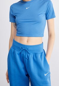 Blå kortärmad t-shirt med rund halsringning och vit Nike-logga, ihop med blå svettbyxor med dragsko och en vit Nike-logga.