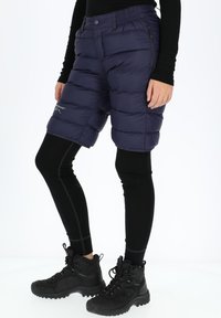 Bermuda navy in cotone con design trapuntato, vita elasticizzata e tasche laterali con zip, abbinati a leggins neri e scarponcini da trekking.