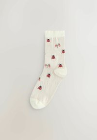 Knielange sokken gemaakt van zachte stof met een crèmekleurige achtergrond, rode lieveheersbeestjes en groene aardbeien op een gestreept patroon.