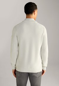Maglione grigio chiaro a maglia con colletto alto e texture a coste, con maniche lunghe e orlo aderente, visto da dietro.