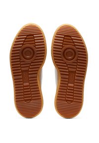 Gumová podešev s texturovaným, vroubkovaným vzorem; oblé loga ve středu; převážně béžová s tmavě hnědými akcenty podél okrajů.