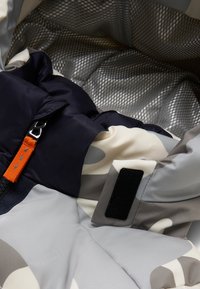 Isoleret sovepose med et grå, hvid og marineblå camo-design. Har en glat, net-foring, en orange detaljeringsrem og velcro-lukning.