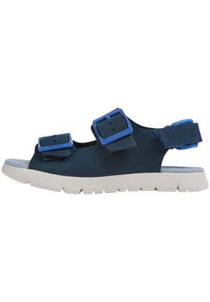 Blå och svarta sandaler med dubbla justerbara spännen, mjuk innersula och en kraftig vit sula med texturerade spår.