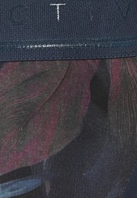 Textile fabric featuring a dark blue textured band above a colorful pattern with shades of purple and dark hues. Visible ribbing detail.