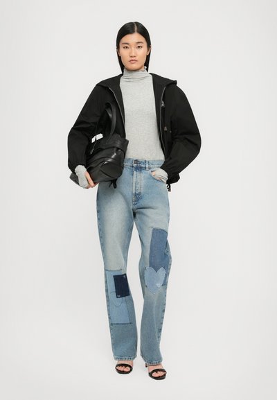 Crna jakna s patentnim zatvaračem, sivi turtleneck, svijetloplave traperice s detaljima patchwork-a u raznim nijansama denima i crne sandale na visoku petu.