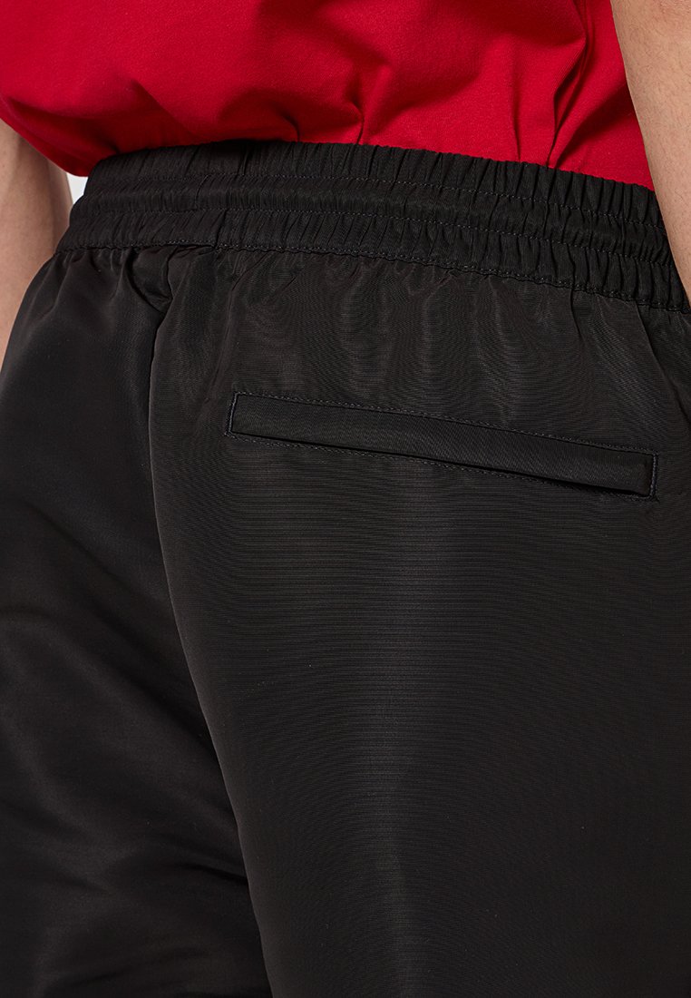 Schwarze Sportshorts aus strukturiertem Gewebe, mit elastischem Bund und einer kleinen Gesäßtasche, die durch ihr elegantes Design funktional ist.