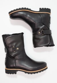 Botas negras de cuero hasta el tobillo con acabado texturizado, forro de piel de pelo, detalle de correa ajustable y suela resistente con patrón.