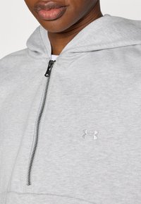 Ανοιχτό γκρι φούτερ με φερμουάρ, κατασκευασμένο από απαλό ύφασμα. Διαθέτει κουκούλα και μικρό κεντητό λογ ότυπο στο στήθος. Το φερμουάρ είναι εμφανές.