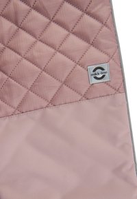Różowa tkanina pikowana z diagonalnym wzorem w diamenty, z gładką dolną częścią i etykietą z szarym obrzeżem z logo "mikk-line".