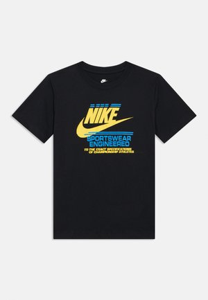 T-shirt en coton noir avec un graphique jaune et bleu audacieux, comprenant le logo Nike et du texte. Col rond, manches courtes, coupe standard.