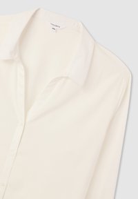 Blusa crema con colletto classico, maniche lunghe e chiusura con bottoni. Realizzata in un tessuto liscio con una leggera consistenza. Taglia 2XL.