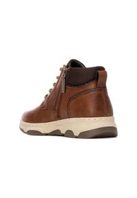 Botín de cuero marrón hasta el tobillo con un cuello de punto texturizado de color marrón oscuro, cremallera lateral y suela de goma de color claro. Detalle elegante con acentos metálicos.